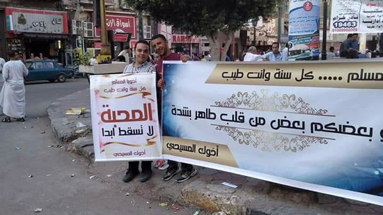Copts in Minya hold signs to congratualte Muslims on the feast
