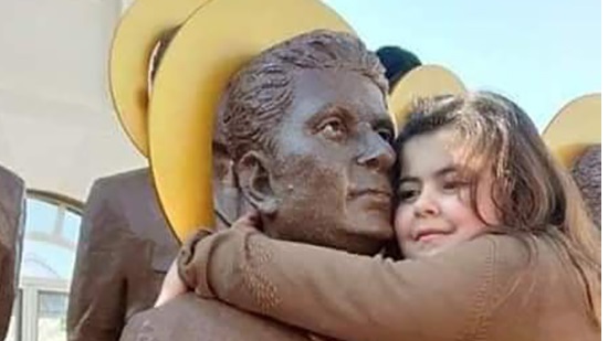 Daughter of martyr Malak Faraj embraces his statue